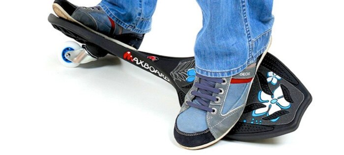 Das Bild zeigt das schwarz-weiss-blaue Waveboard Kinder black hibiscus bei dem zwei Füße die Waveboard-Plattformen gegeneinander verdrehen
